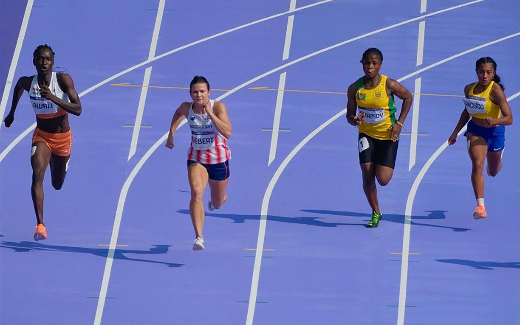 Leichtathletikbahn mit vier Läuferinnen beim 100-m-Lauf bei den Olympischen Spielen in Paris.